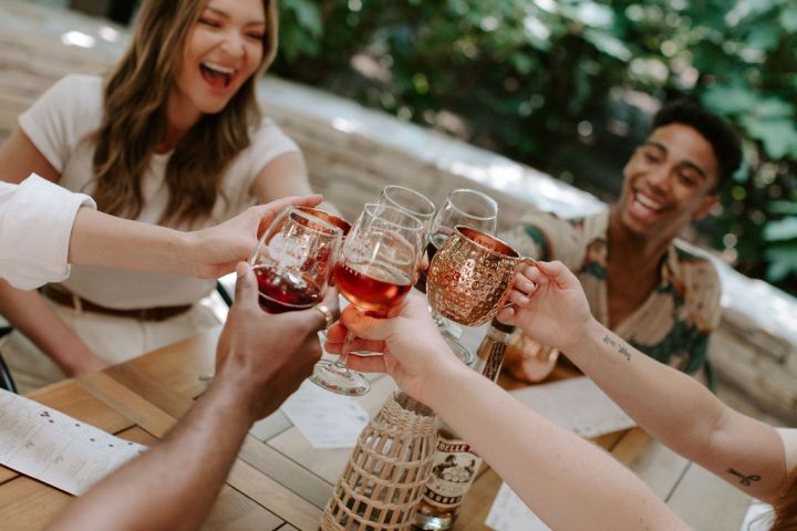 People toasting with drinks at an outdoor table.