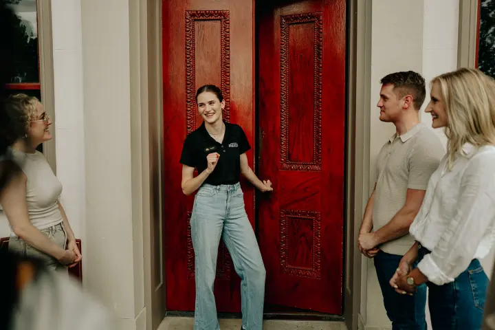 Smiling group of four people talking in front of red doors.