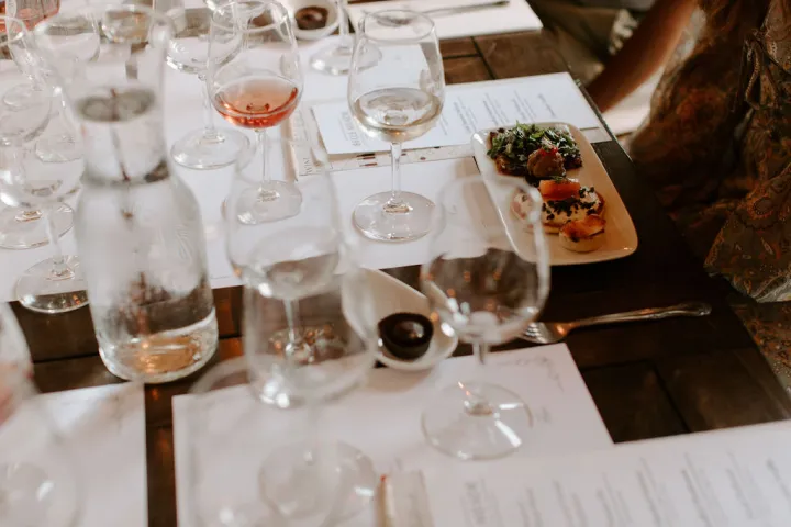 Table with empty wine glasses, water bottle, and plated appetizers.