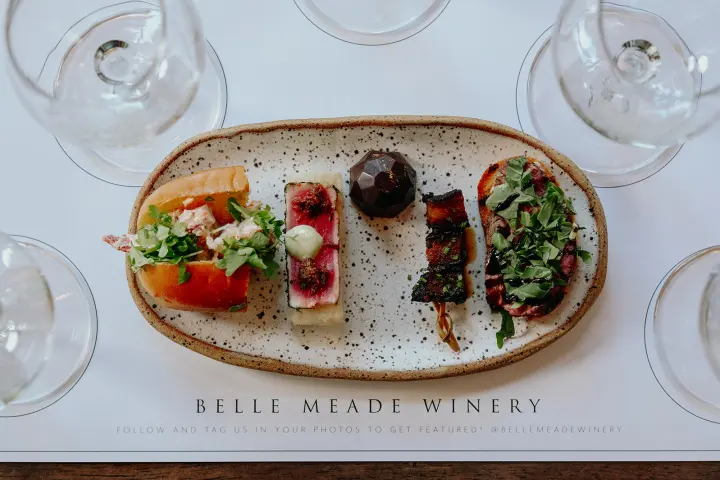 Assorted hors d'oeuvres on a speckled platter with wine glasses.