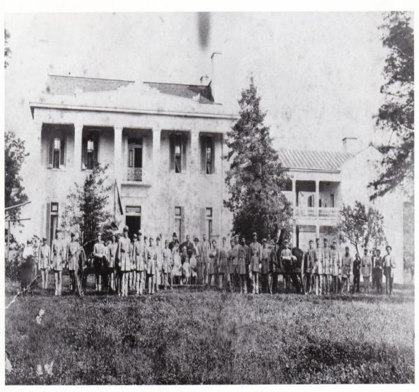 a vintage photo of a group of people standing in front of a house