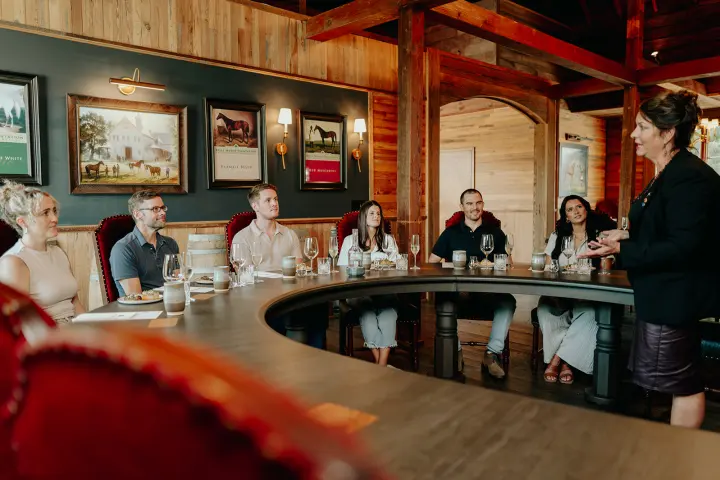 A group of people seated at a round table listening to a speaker.