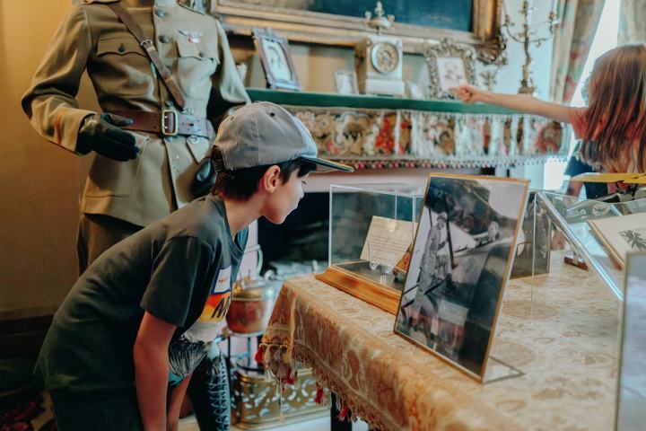 Child looking at museum displays with historical uniform and framed photos.
