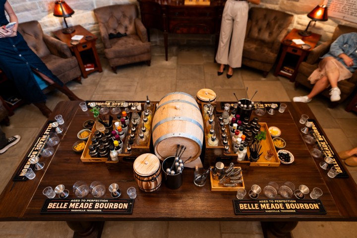 Table with a barrel, bottles, and tasting glasses in a cozy room setting.